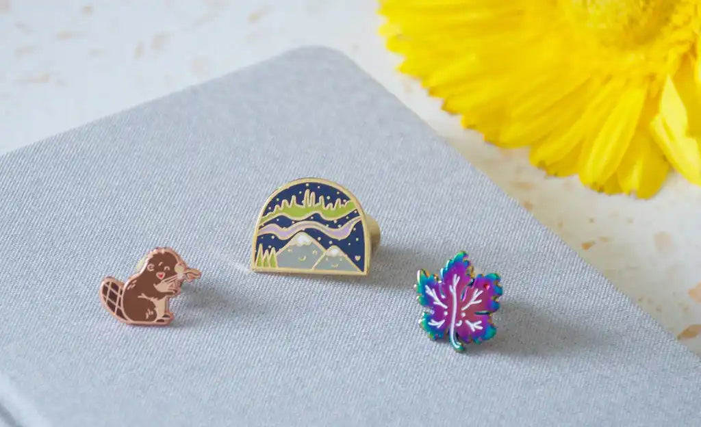 Three colorful enamel pins.