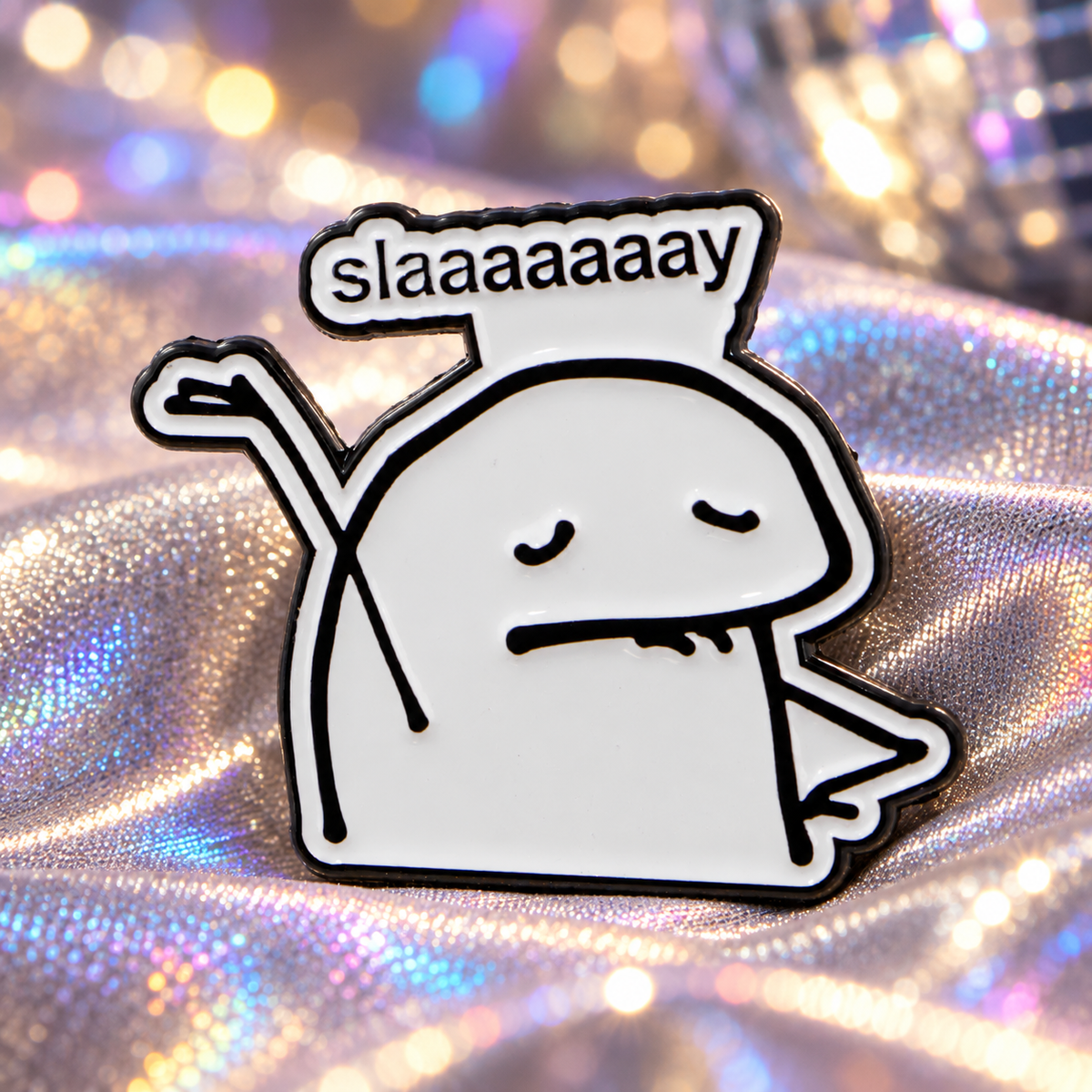 Slay enamel pin on iridescent silver fabric with stage-light bokeh