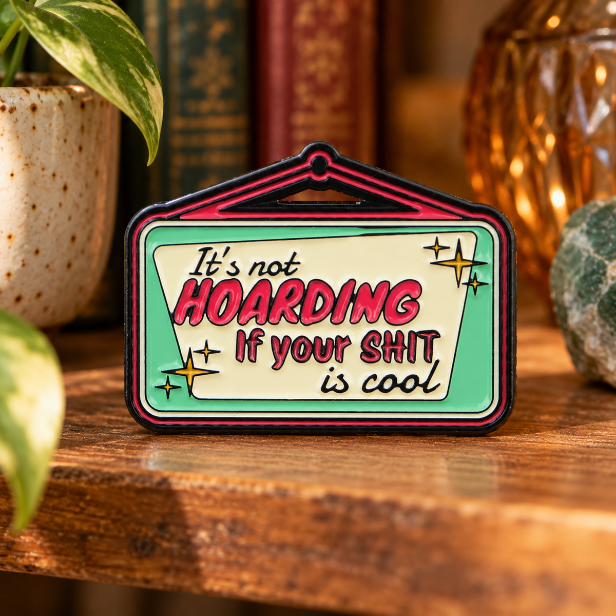 It's Not Hoarding If Your Shit Is Cool enamel pin on a cozy collector shelf