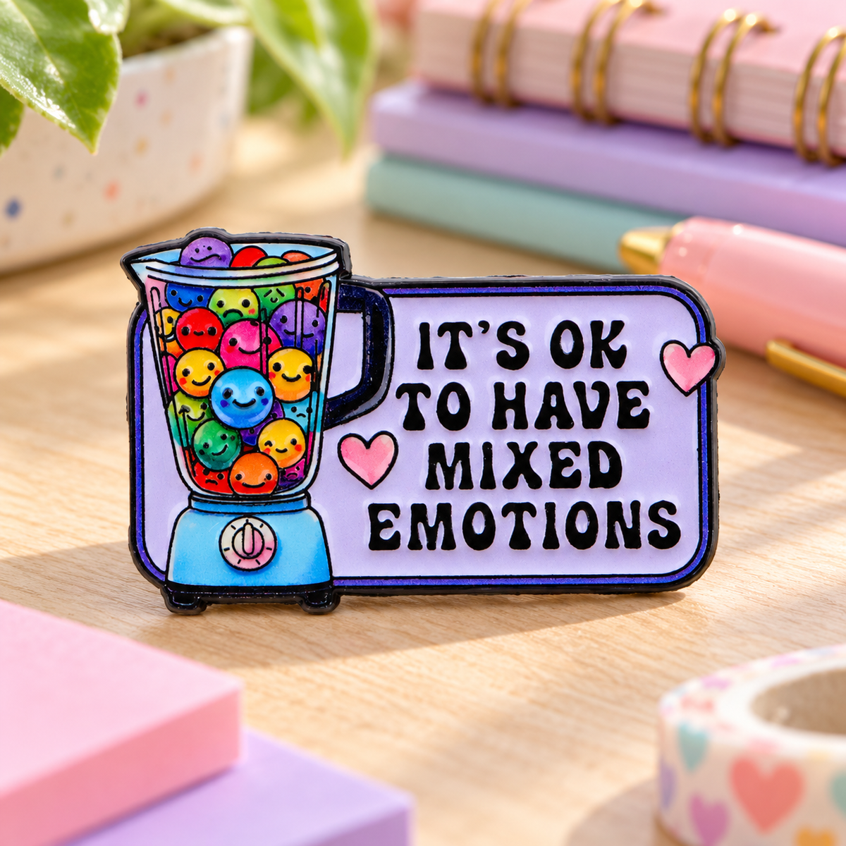 It's Ok To Have Mixed Emotions enamel pin on a colorful desk