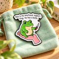 Emotional support frog with a knife enamel pin on mint fabric
