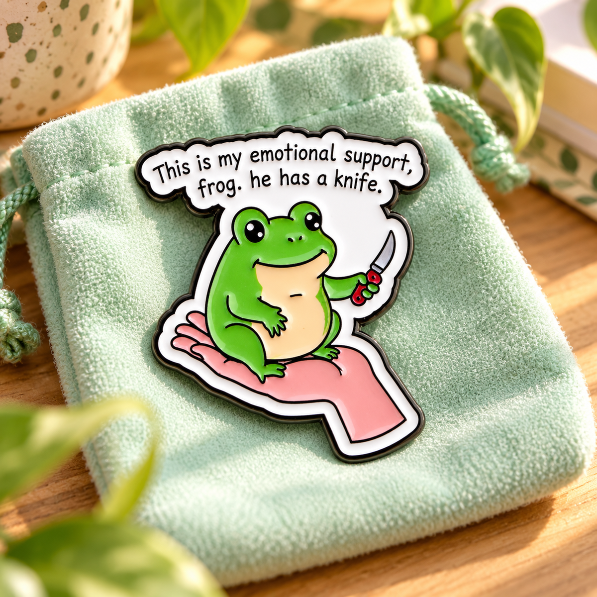 Emotional support frog with a knife enamel pin on mint fabric