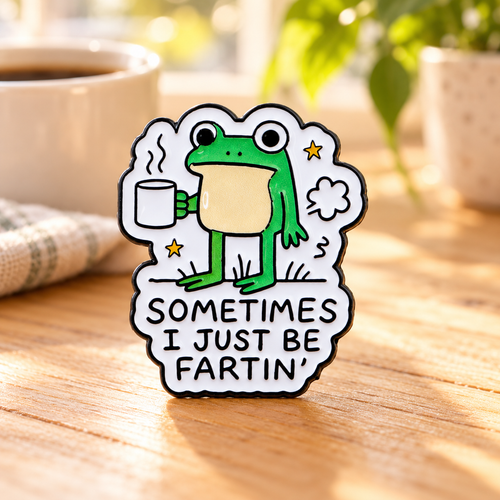 Sometimes I Just Be Fartin' Frog Pin on a sunny cafe table