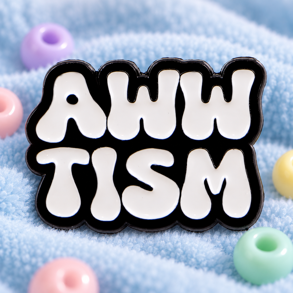 Awwtism enamel pin displayed on soft light-blue sensory fabric with pastel beads