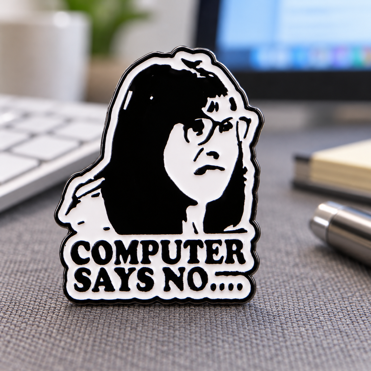 Computer Says No Carol Beer enamel pin in an office setting
