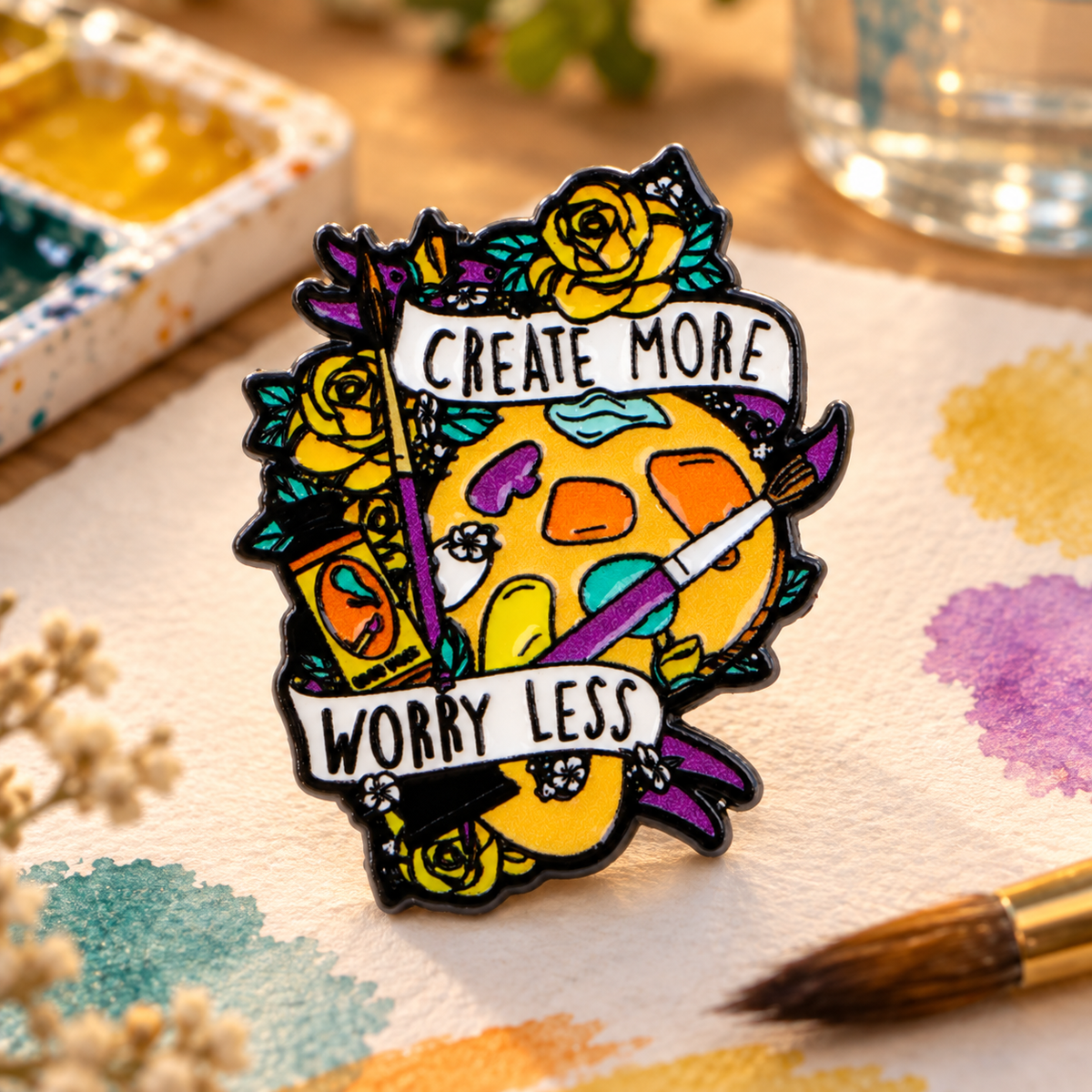 Create More Worry Less artist palette enamel pin in a watercolor studio