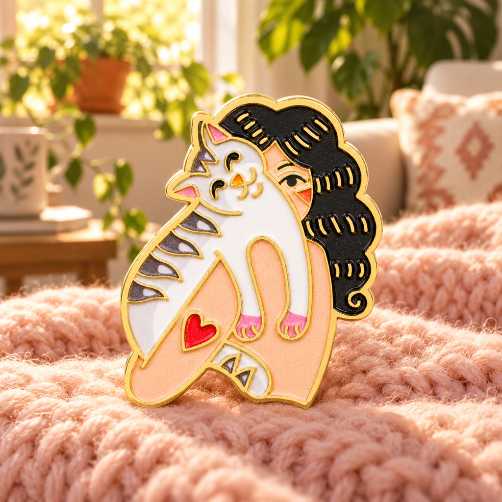 Curly-Haired Cat Lover enamel pin on a cozy pink blanket