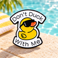 Don't Duck with Me sunglasses enamel pin beside a sunny pool