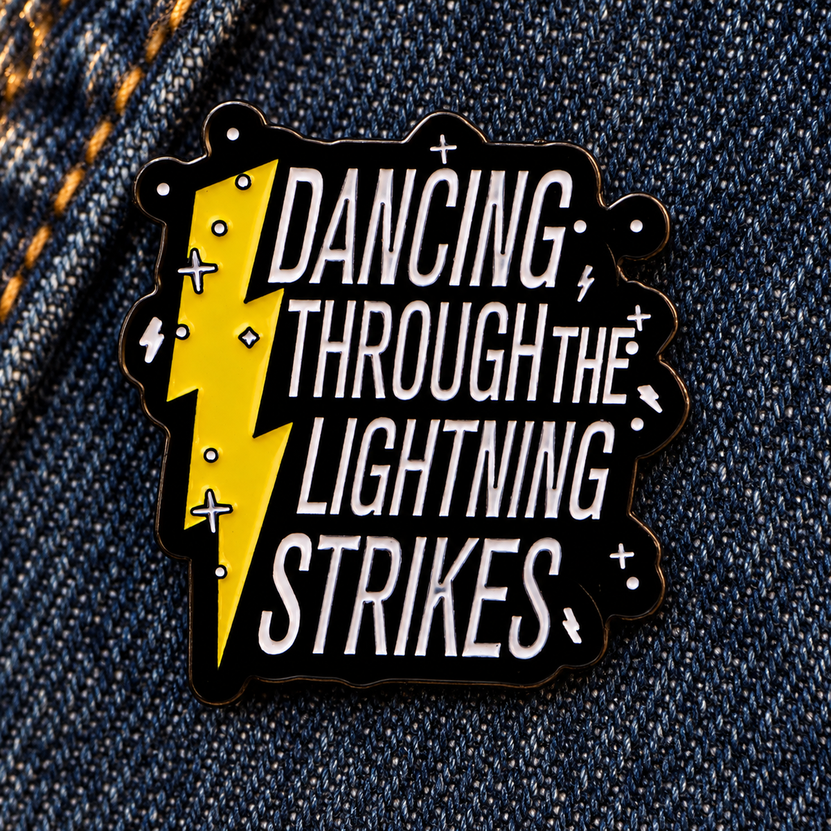 Dancing Through The Lightning Strikes enamel pin on indigo denim