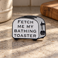Fetch Me My Bathing Toaster enamel pin on a retro kitchen counter