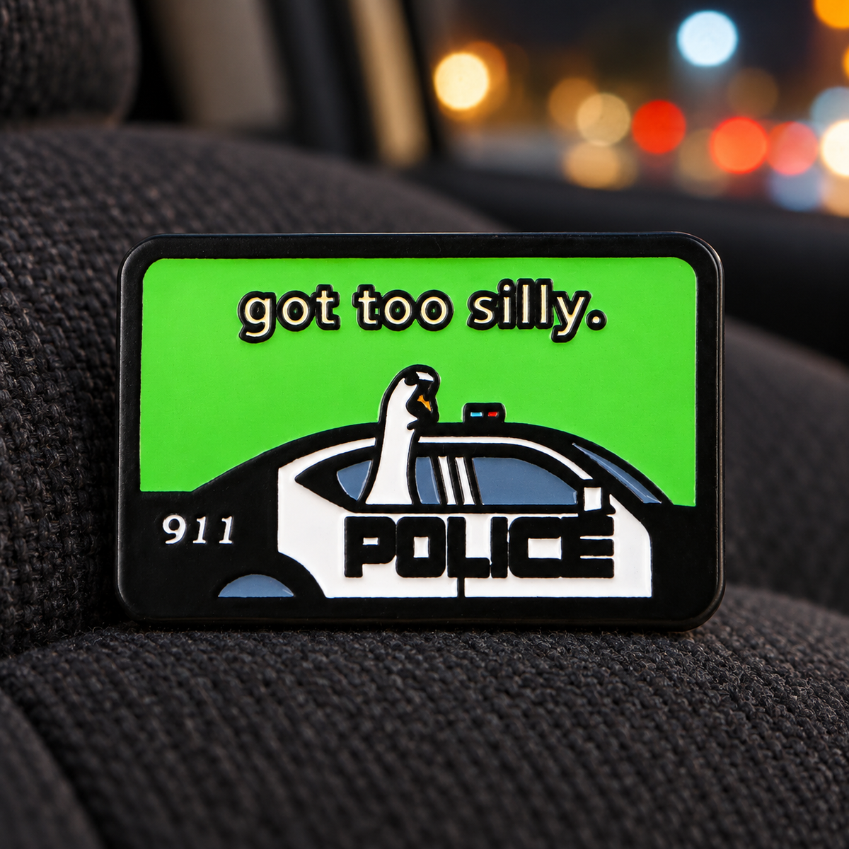 Got Too Silly Goose police car enamel pin on a car seat