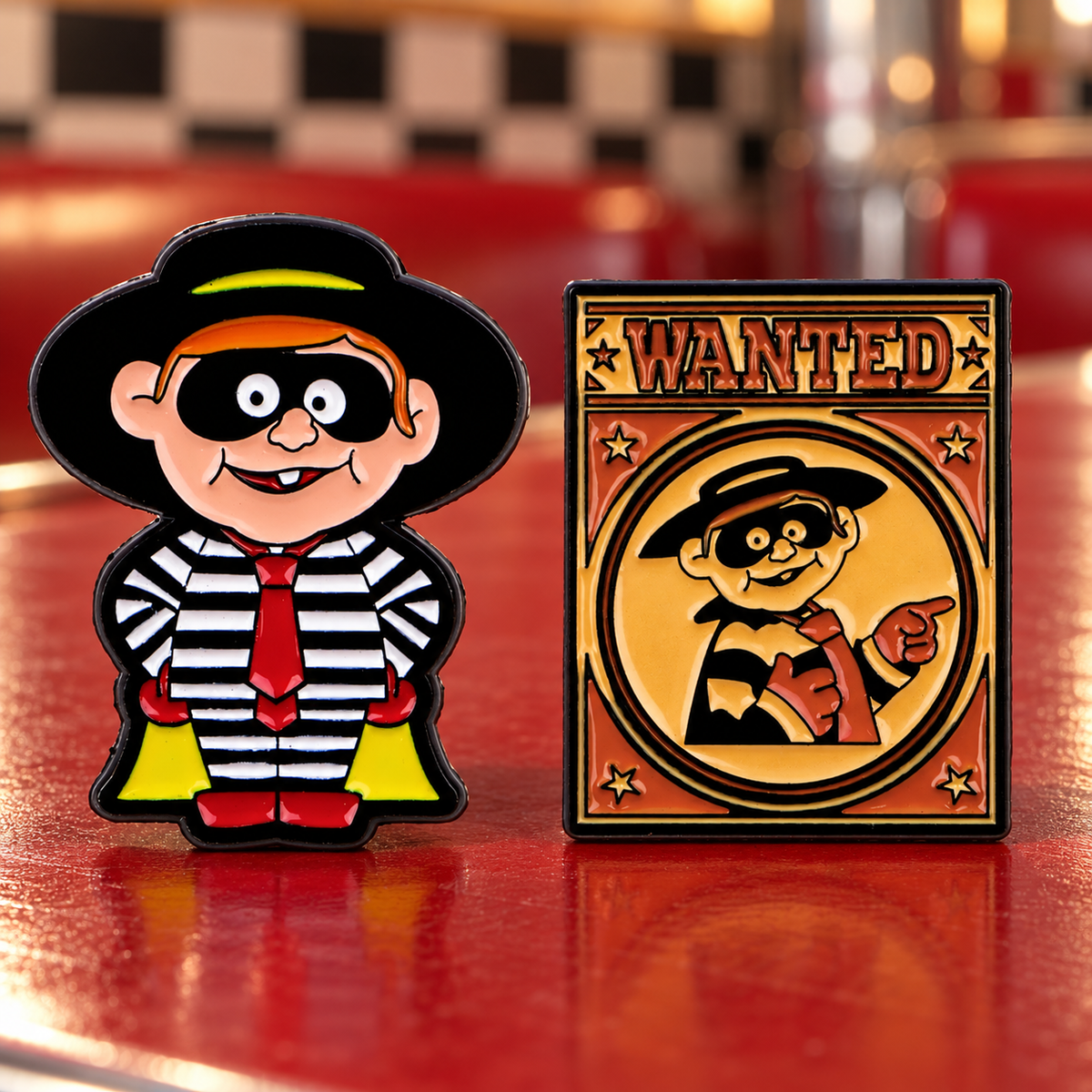 Two Hamburglar enamel pins on a retro diner tabletop