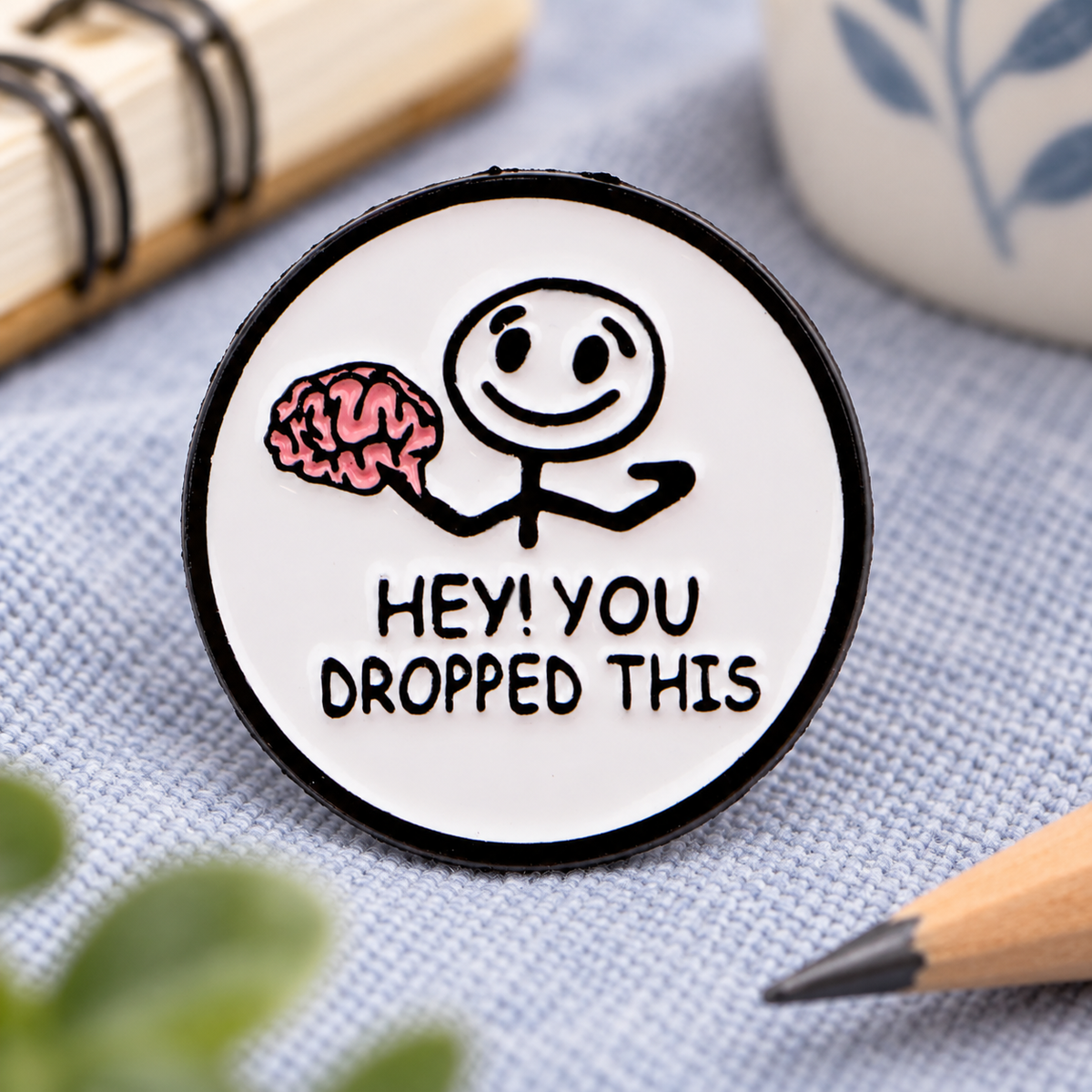 Hey You Dropped This brain enamel pin on a study desk