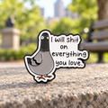 I Will Shit on Everything You Love pigeon enamel pin on a sunlit urban park ledge