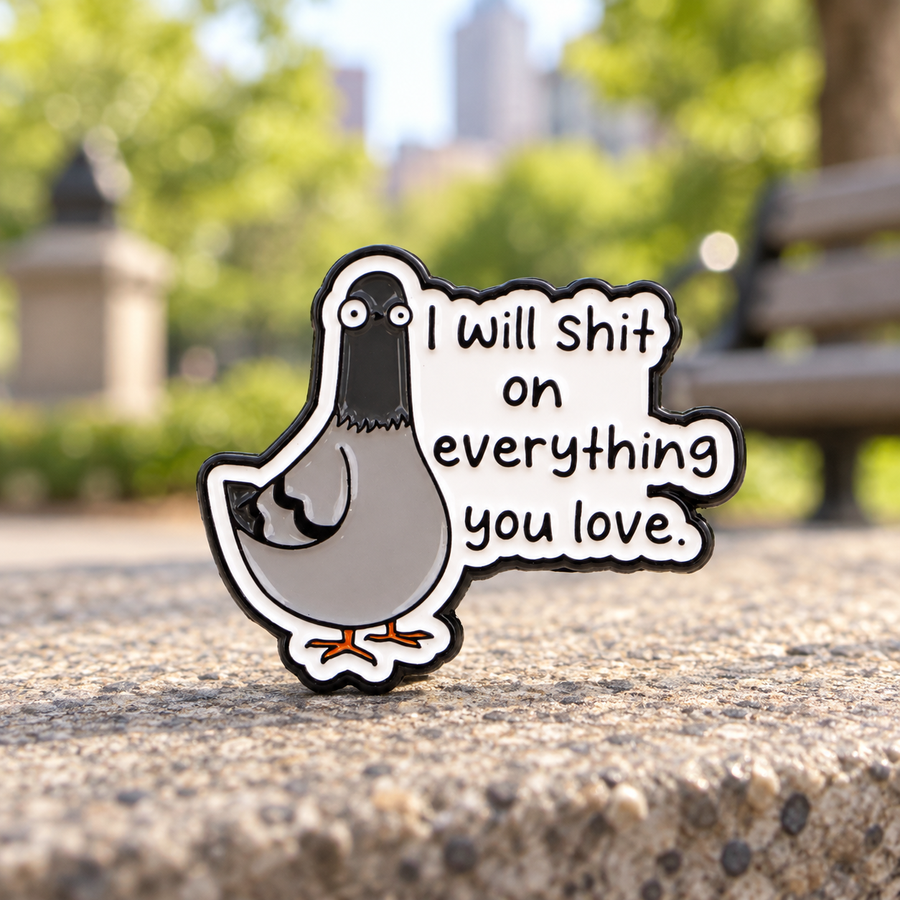 I Will Shit on Everything You Love pigeon enamel pin on a sunlit urban park ledge