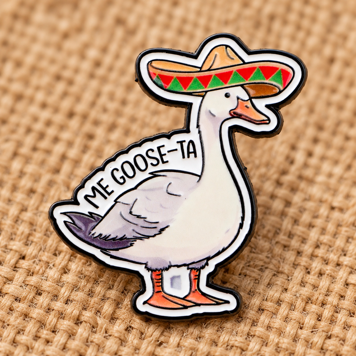 Me Goose-Ta enamel pin on tan woven fabric