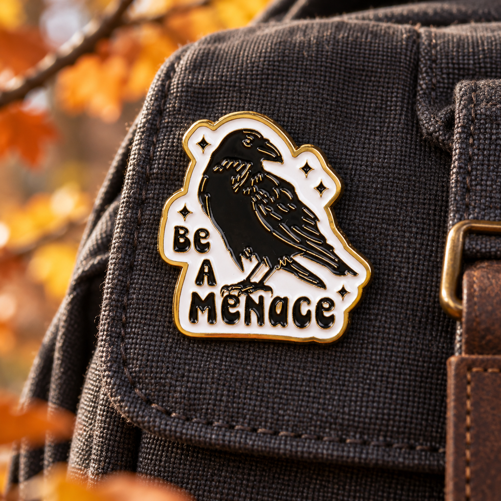 Be A Menace Crow enamel pin on a charcoal backpack