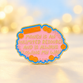 Money Is an Unlimited Resource affirmation enamel pin on a warm pastel backdrop
