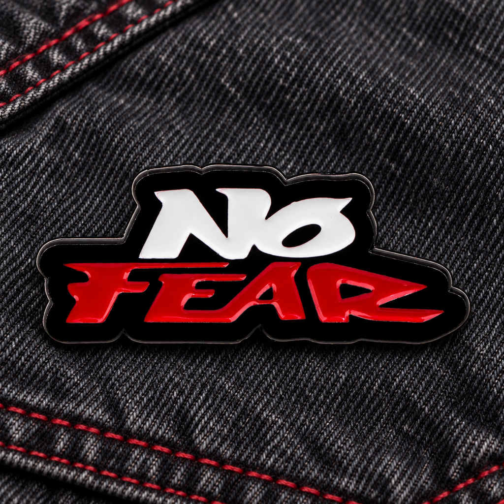 No Fear enamel pin on dark denim with red stitching