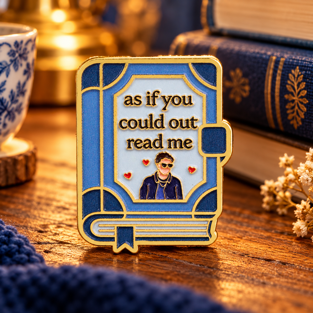 As If You Could Outread Me enamel pin on a cozy reading table
