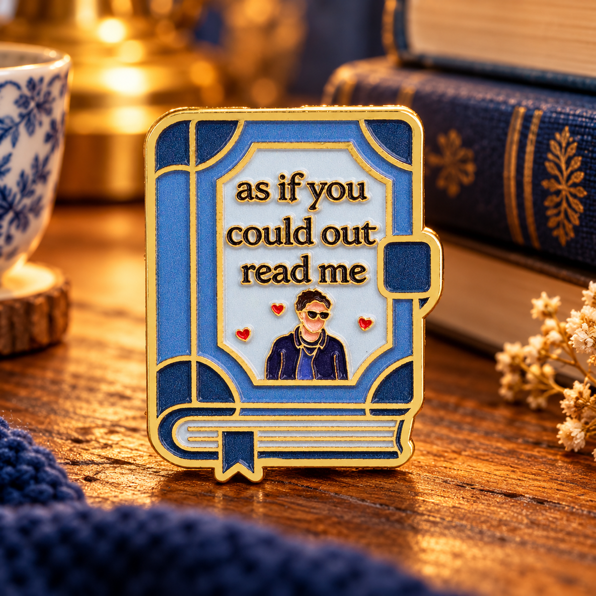 As If You Could Outread Me enamel pin on a cozy reading table