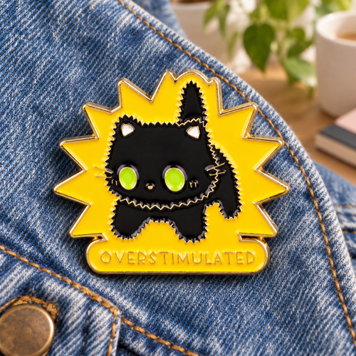 Overstimulated black cat enamel pin on a blue denim jacket