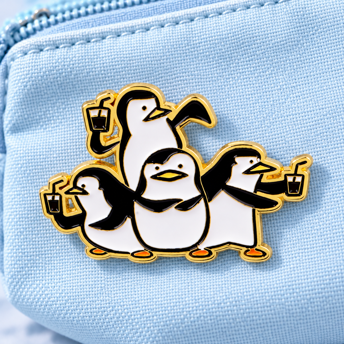 Four penguin enamel pin on icy blue canvas