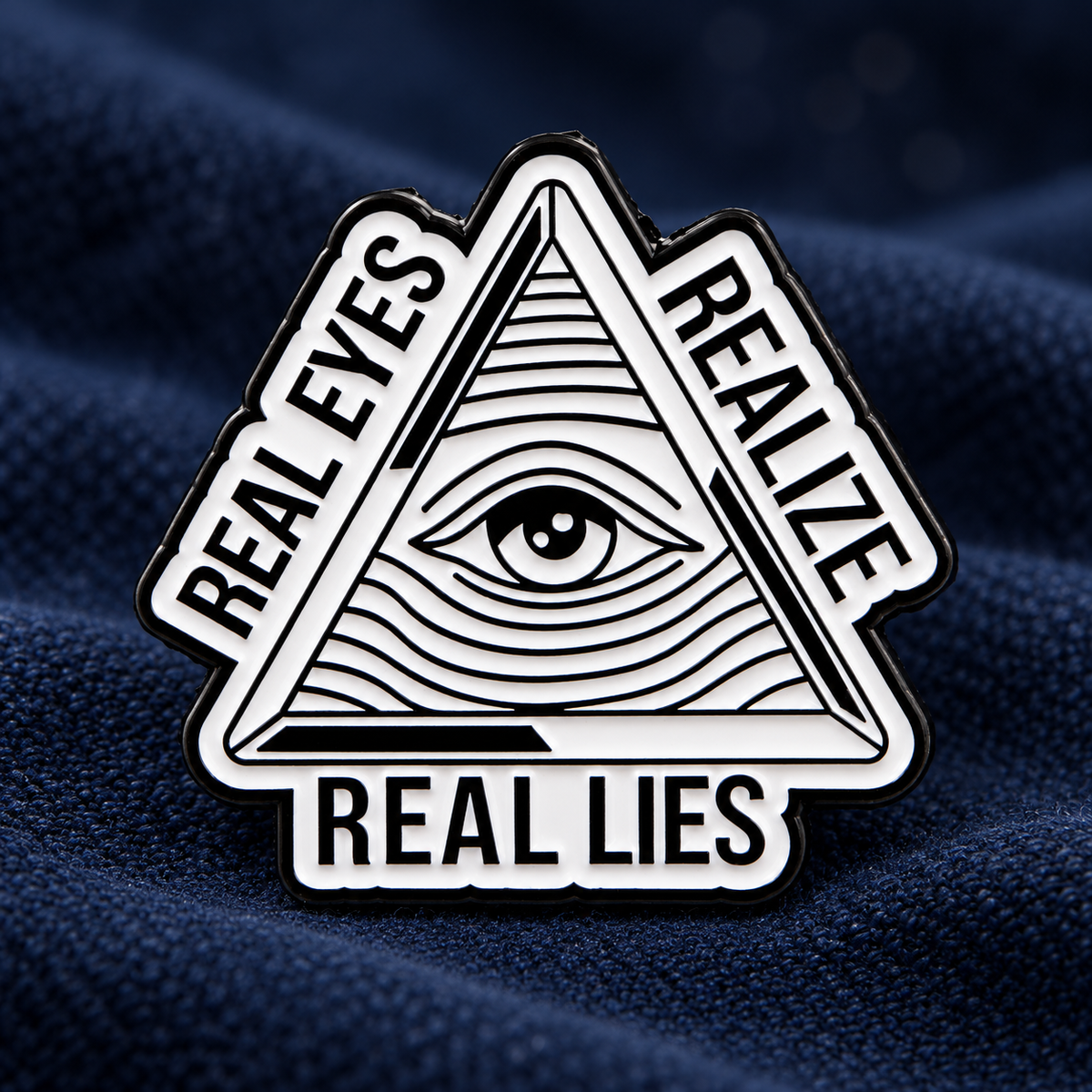 Real Eyes Realize Real Lies enamel pin on navy fabric