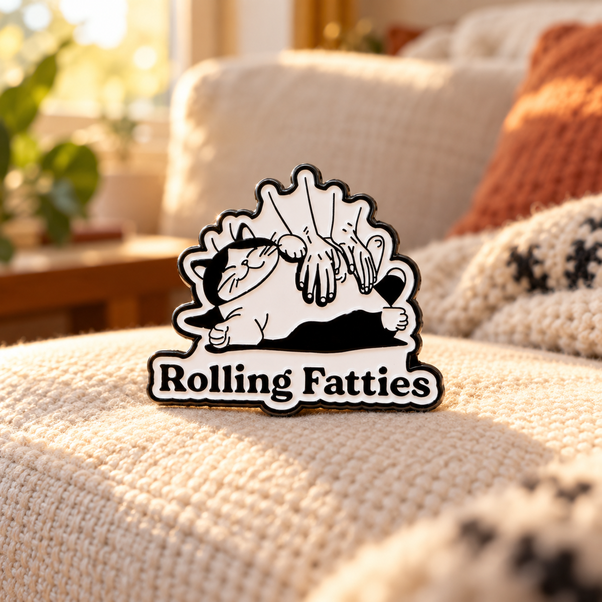 Rolling Fatties Cat Pin on a cozy living room blanket