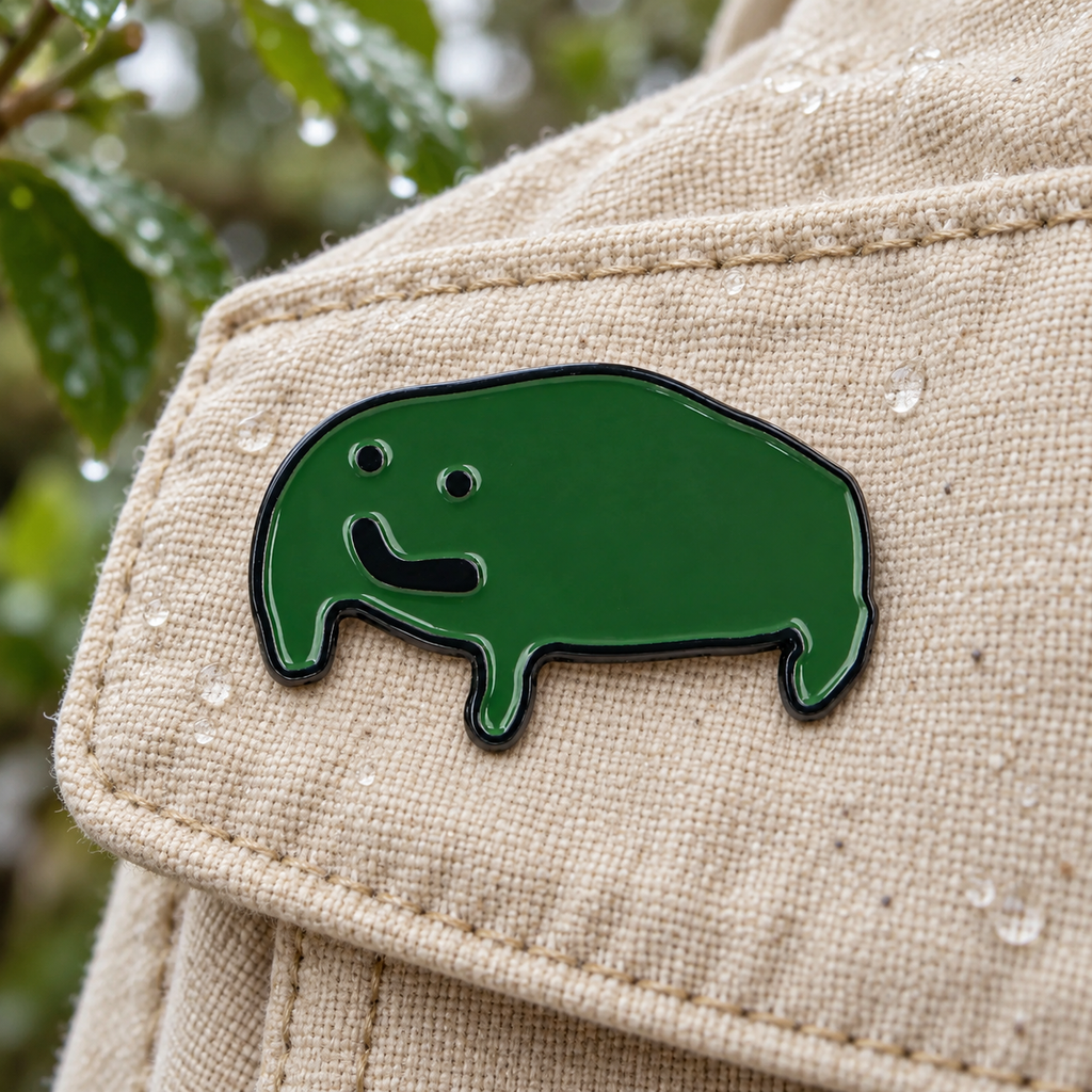 Sad Frog enamel pin on a canvas jacket after rain