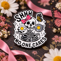 Shhh No One Cares Skeleton Pin enamel pin on a themed background