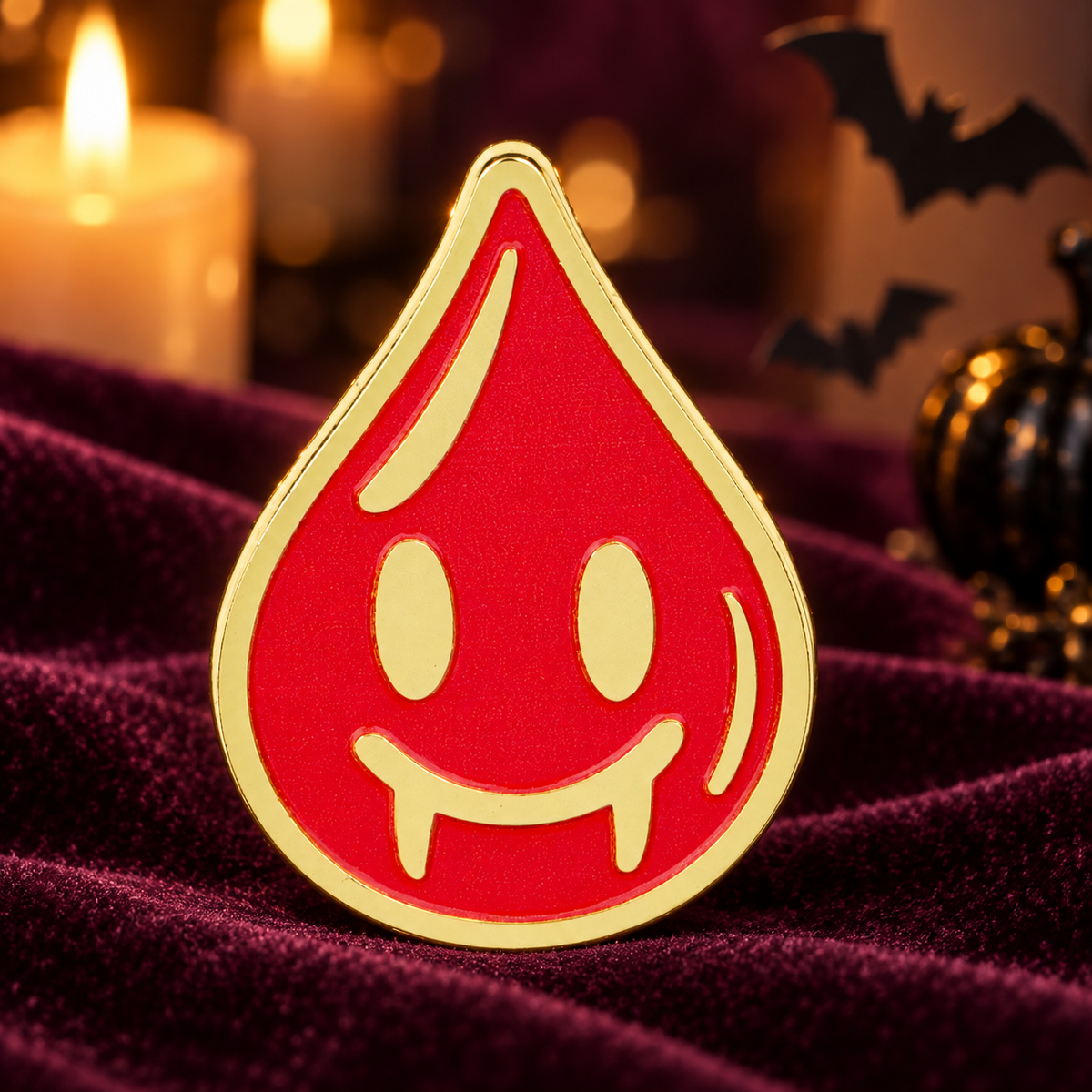 Smiling vampire blood drop enamel pin on plum velvet with Halloween lights