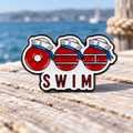 SWIM sailor enamel pin beside the sea