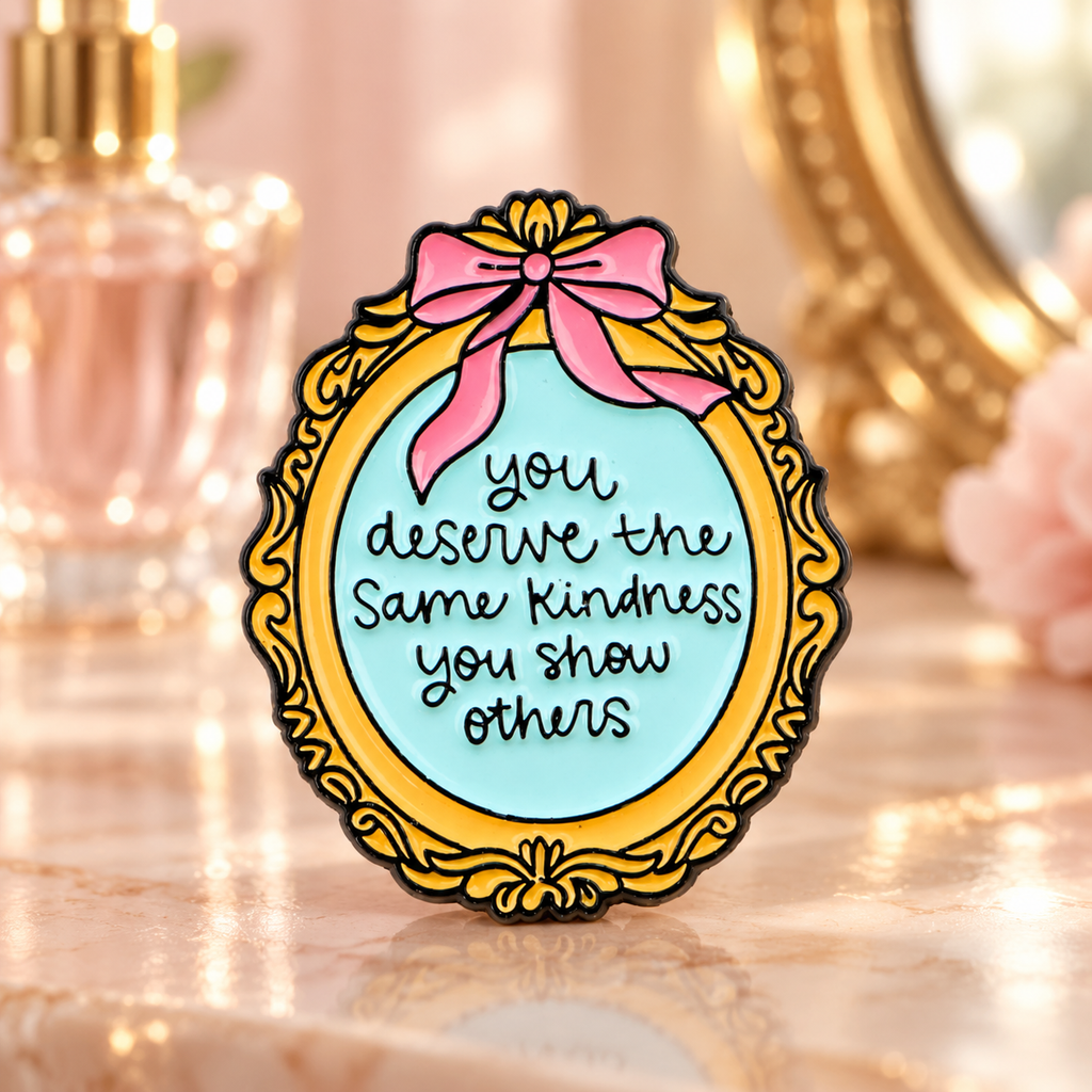 You Deserve the Same Kindness mirror enamel pin on a warm vanity table