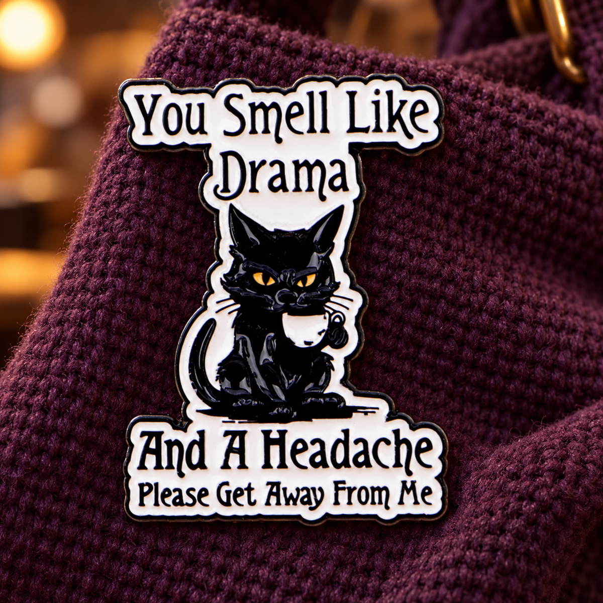 You Smell Like Drama black cat enamel pin on plum knit fabric